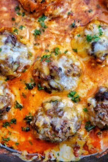 Juicy Tex-Mex meatballs topped with melted Mexican cheese in a smoky chipotle tomato sauce, garnished with fresh parsley in a cast-iron skillet.