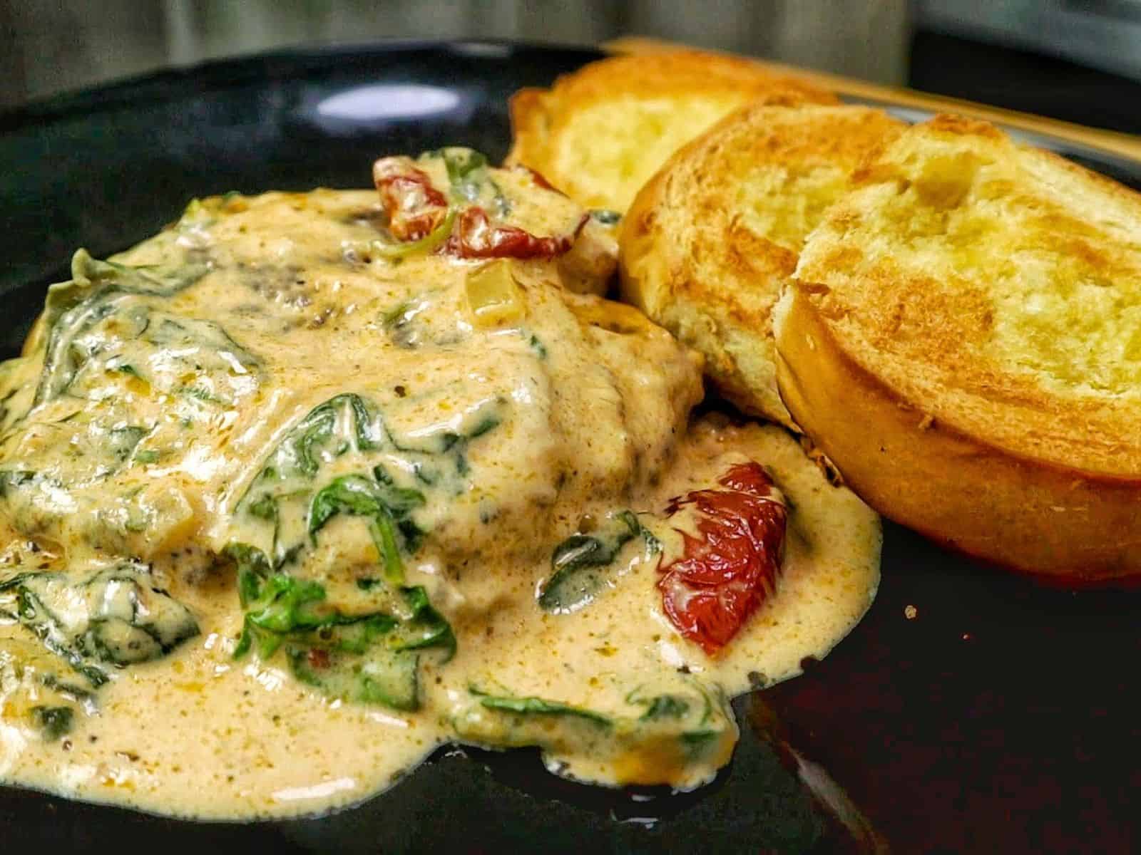 Pan-seared Tuscan Hamburger Steaks simmering in a rich Parmesan cream sauce with spinach, garlic and sun-dried tomatoes in a large skillet.